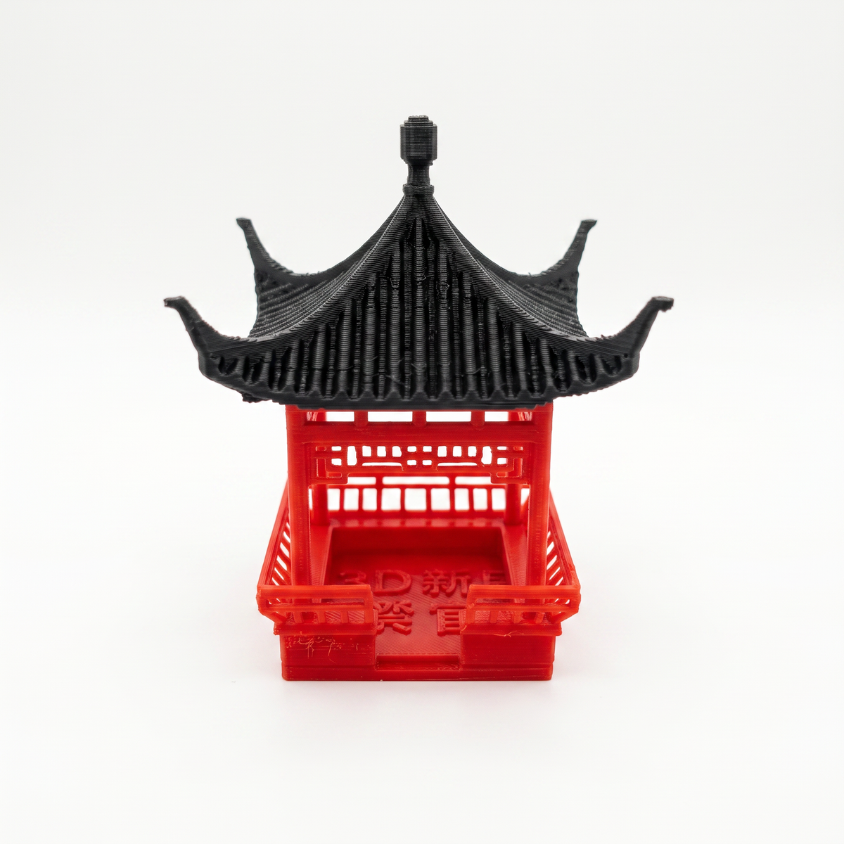 A miniature red and black plastic pagoda model, likely a 3D-printed toy or miniature, shown from a front-facing perspective on a seamless white background.